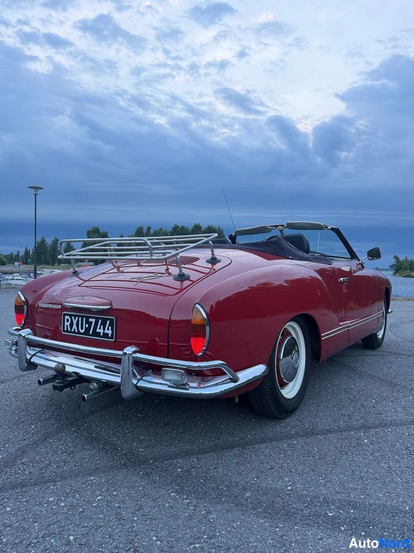 Takaviisto: Tummanpunaisen Volkswagen Karmann-Ghia -cabrioletin takapää ja vasen kylki rekisterikilvellä, krominen matkatavarateline takakannella.
