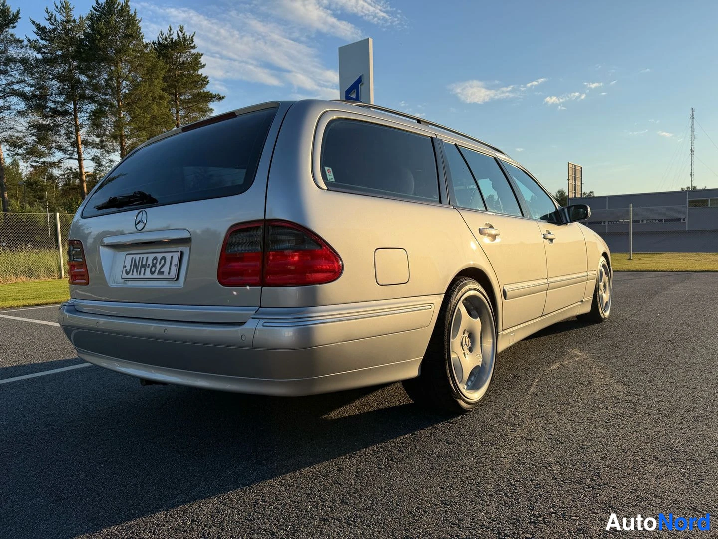 Takaviisto: Hopeanvärinen Mercedes-Benz farmariauto takaa kolmivartalokulmasta kuvattuna, rekisterikilpi näkyvissä.