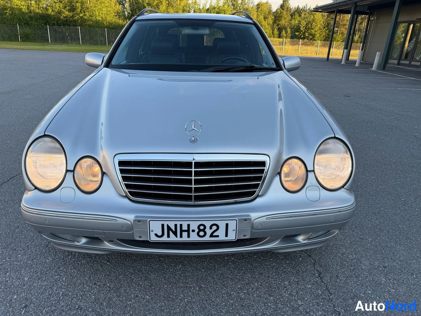 Edestä: Farmarimerkki hopeanvärinen Mercedes-Benz suoraan edestä, rekisteritunnus.