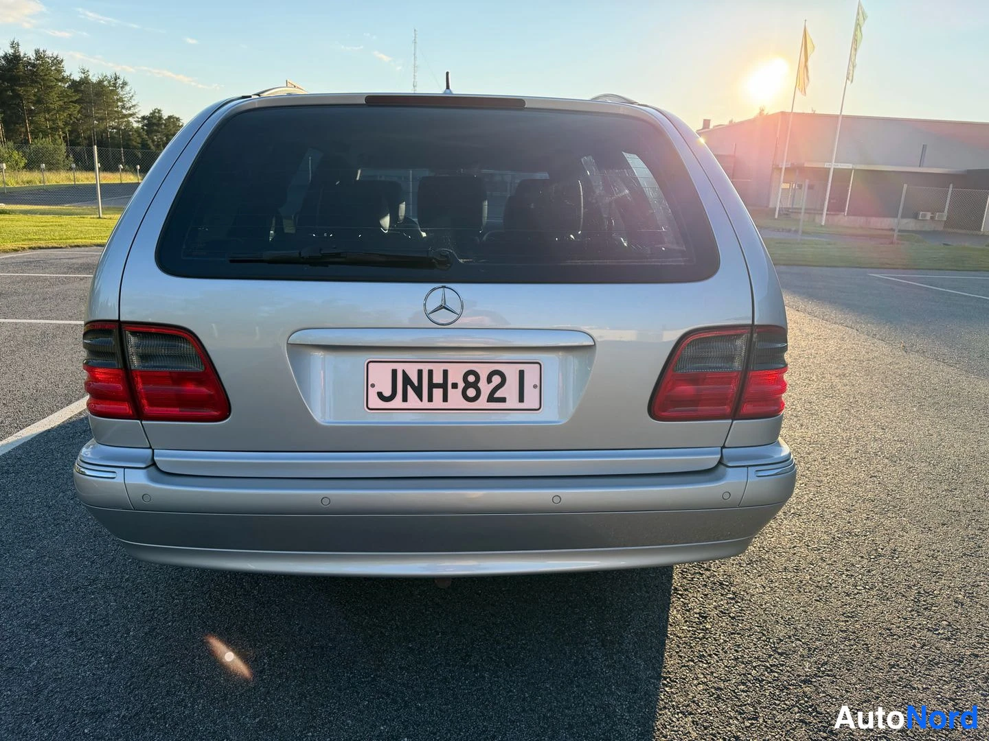 Takaa: Auto takaapäin: hopeinen farmarimerkki, punaiset takavalot ja rekisterikilpi.