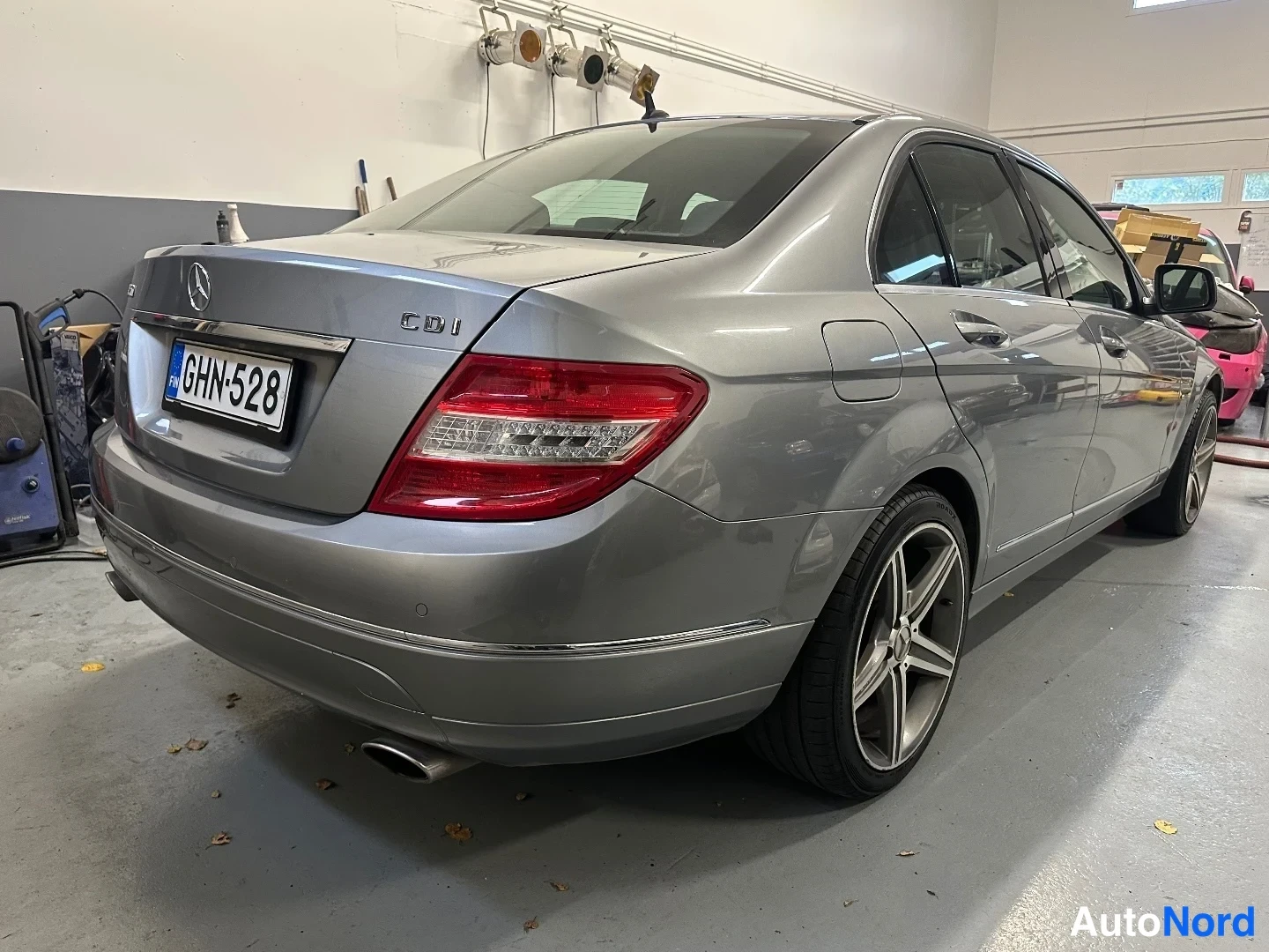 Takaviisto: Auto takaa vasemmalta kuvattuna autotallissa: rekisterikilpi, CDI-teksti ja hopeinen kori.