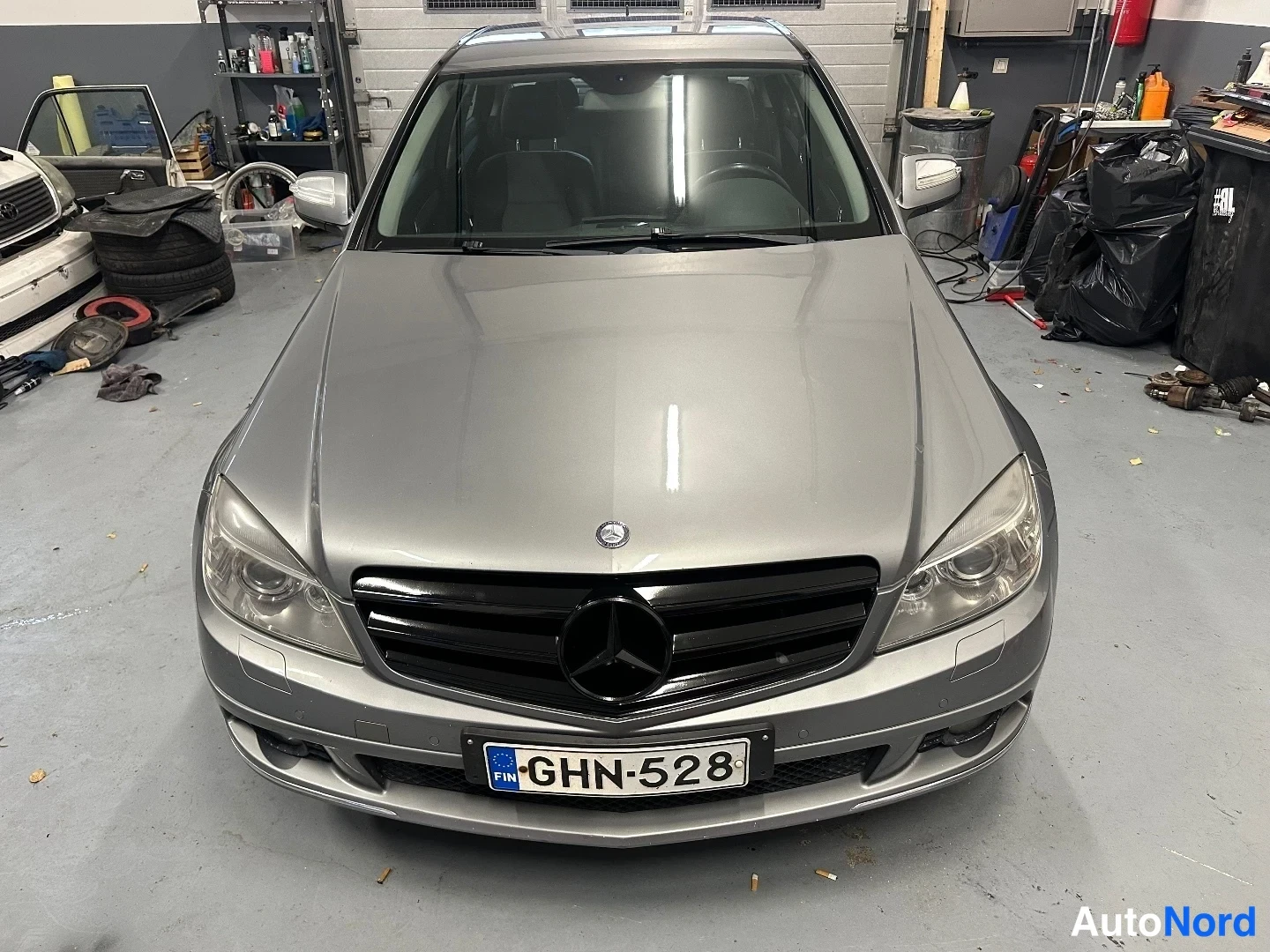 Edestä: Mercedes-Benz C 320 CDI Avantgarde 2007, hopeanvärinen sedan edestä kuvattuna hallissa, rekisterikilpi