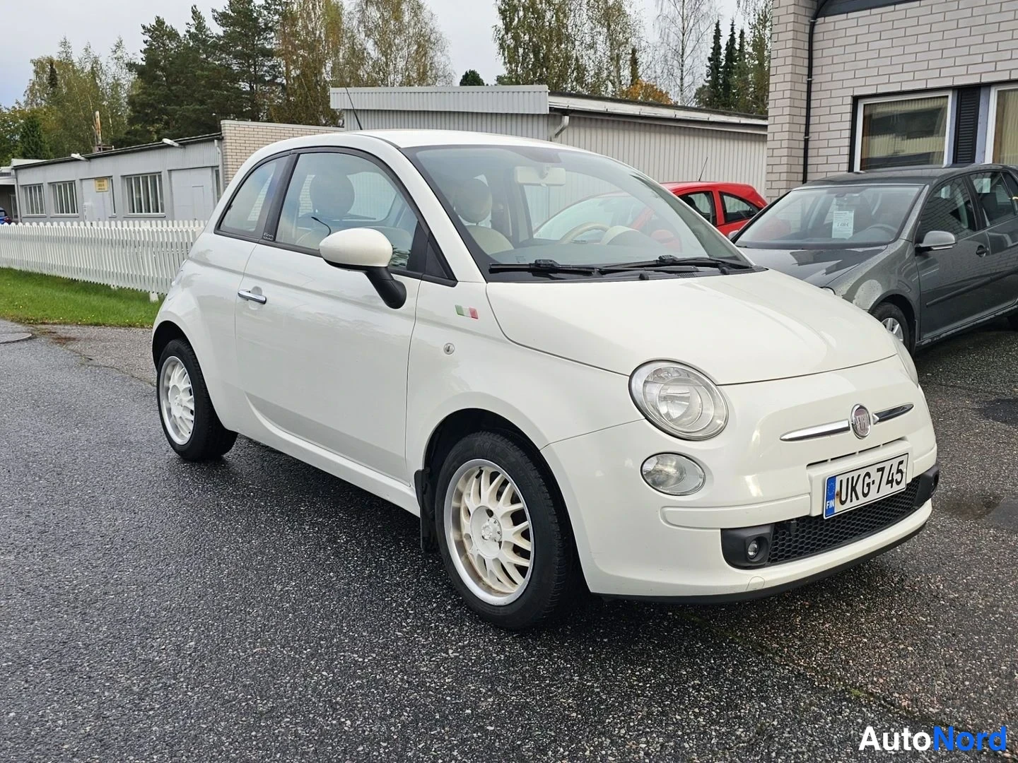Etuviisto, nokka oikealle: Fiat 500, valkoinen, etuosa ja vasen kylki näkyvät kolmeneljännes­kuvassa parkkipaikalla