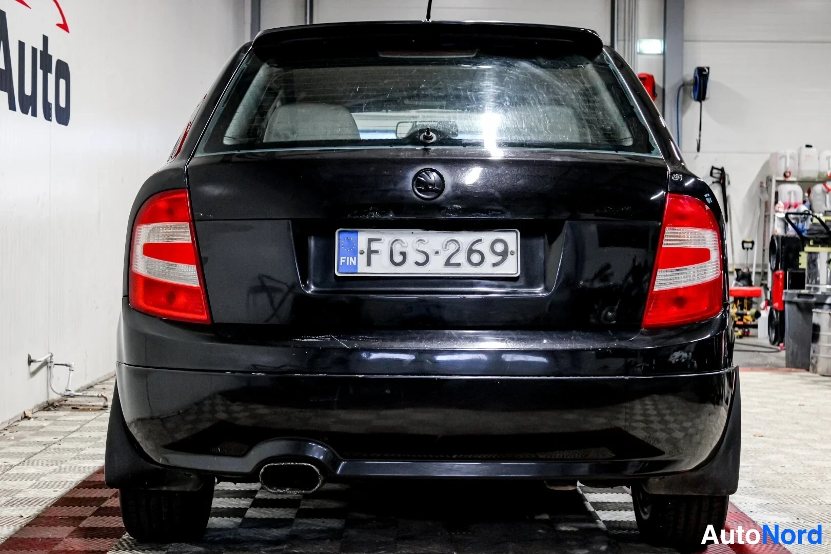 Takaa: Mustan hatchbackin suora takaosa, rekisterikilpi ja keskellä sijaitseva pakoputki näkyvät.