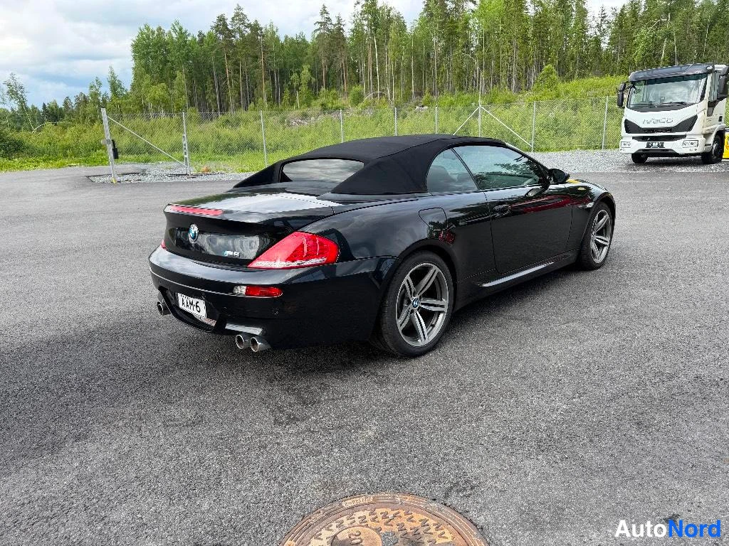 Takaviisto: Rear three-quarter shot capturing the left flank and rear face of the car, highlighting the red tail lights, black soft-top roof, and rear diffuser.