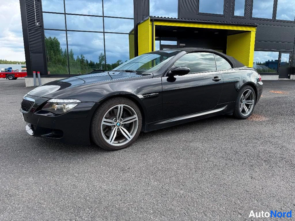 Etuviisto, nokka vasemmalle: Musta avoauto BMW sivukulmassa, keula vasemmalla