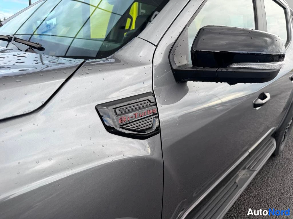 Sivulta: Sivunäkymä autosta: etummaisen lokasuojan musta Bi-Turbo-merkki ja musta sivupeili, kori harmaa.