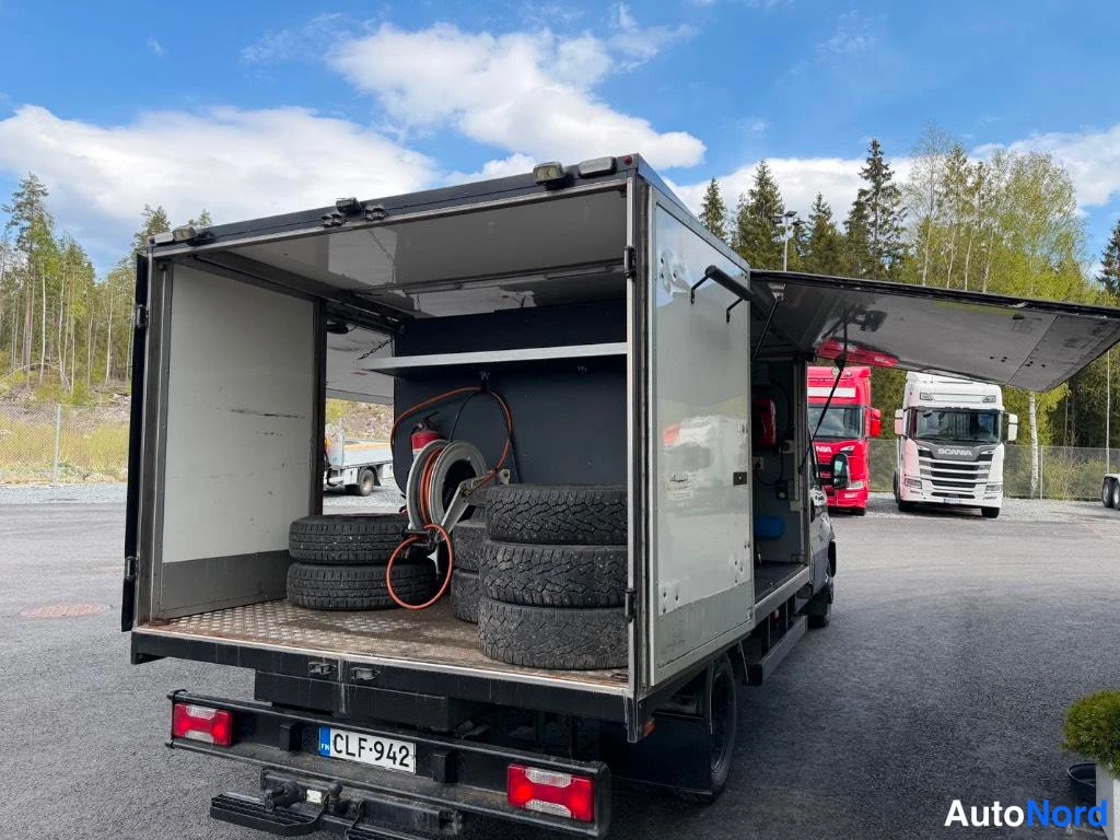 Takaa: Rear view of the Iveco Daily showing open service body with spare tires and equipment inside.