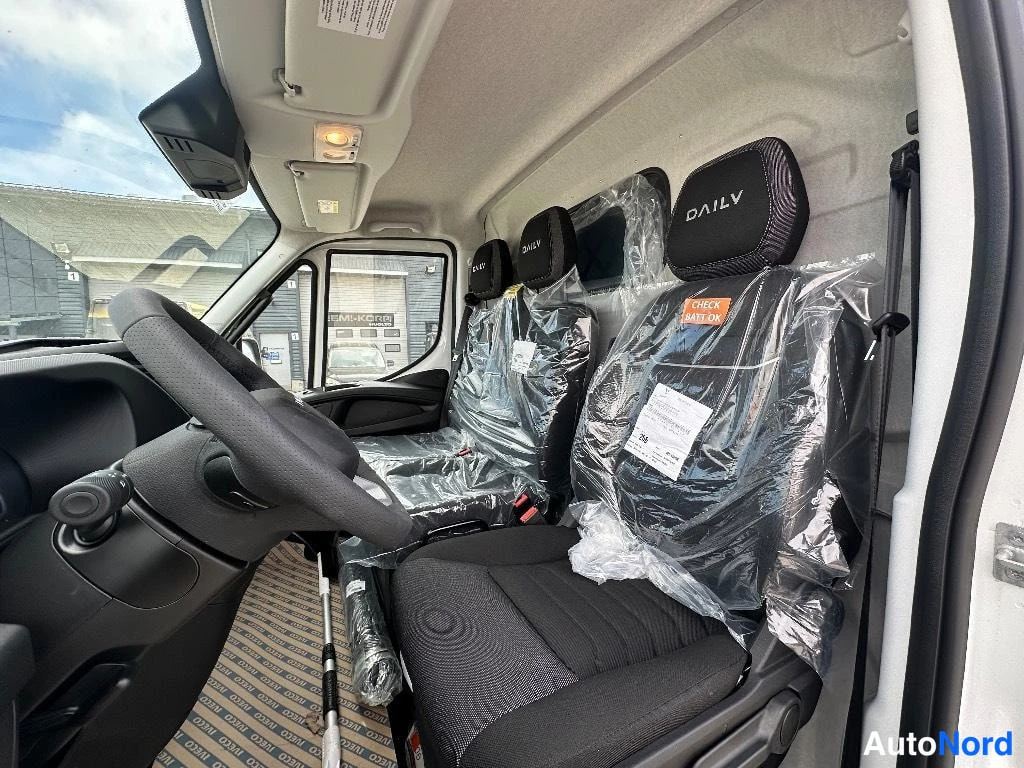 Takaa: Iveco DAILY -pääntuetteiset istuimet kolme rinnakkain, suojamuovissa, matkustamo katsottu takaapäin.