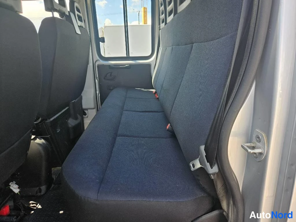 Takaistuimet: Interior view of a dark blue fabric rear bench seat in a van, showing three seat cushions, backrests, headrest cutouts, and seatbelt buckles.