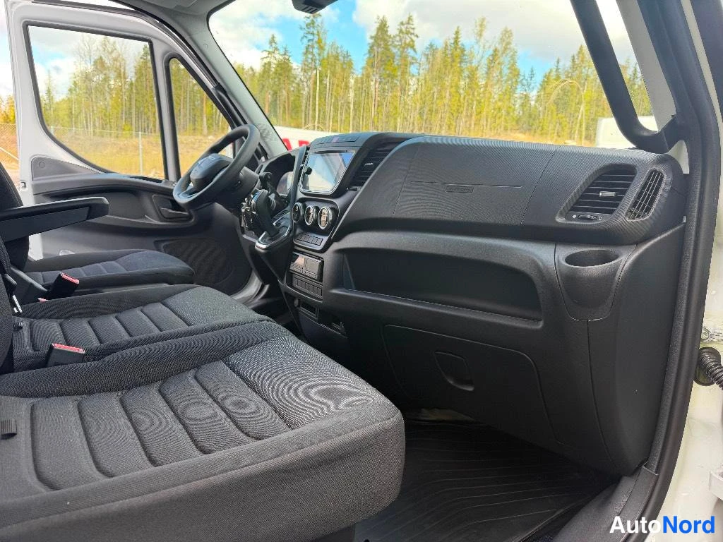 Muu: Pakettiauton ohjaamo kuvattuna matkustajan puolelta: tumma kangaspenkki, kojelauta, Ohjaustehostin-teksti ja kosketusnäyttö radio/karttatoiminnolla.