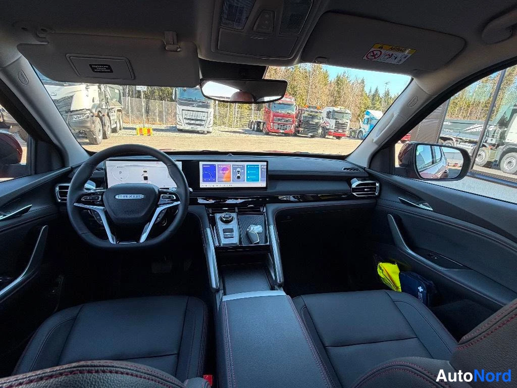 Muu: Autoen ohjaamo kuvattuna taakse: musta MAXUS-tunnuksellinen ohjauspyörä, suuri keskinäyttö ja kaksinkertainen paneelinäyttö.