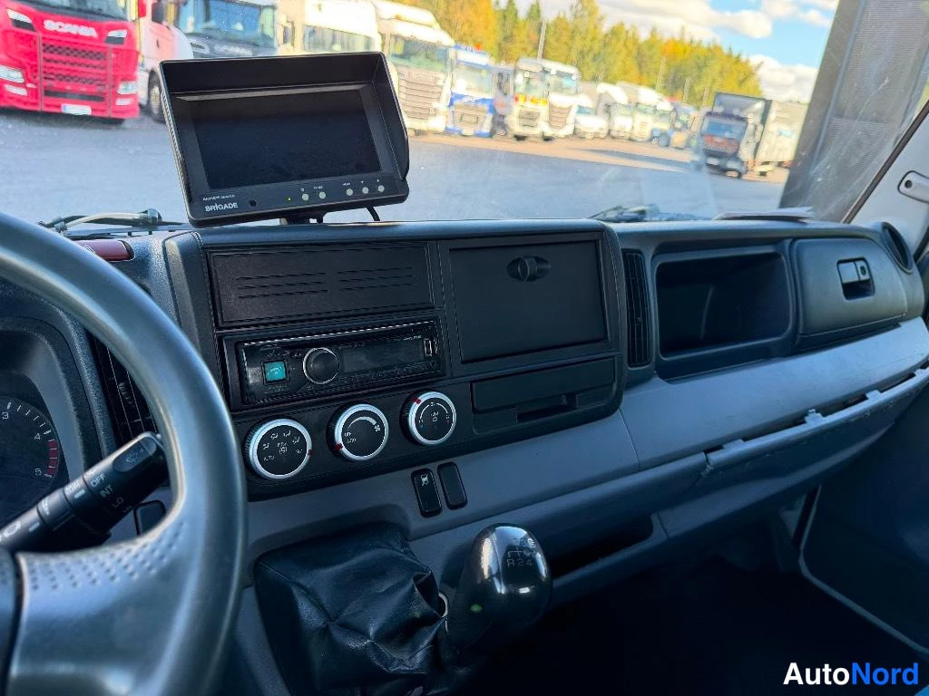 Muu: Kuorma-auton ohjaamo: radio,ilmastointisäätimet ja Brigade-niminen monitori tuulilasin takana.