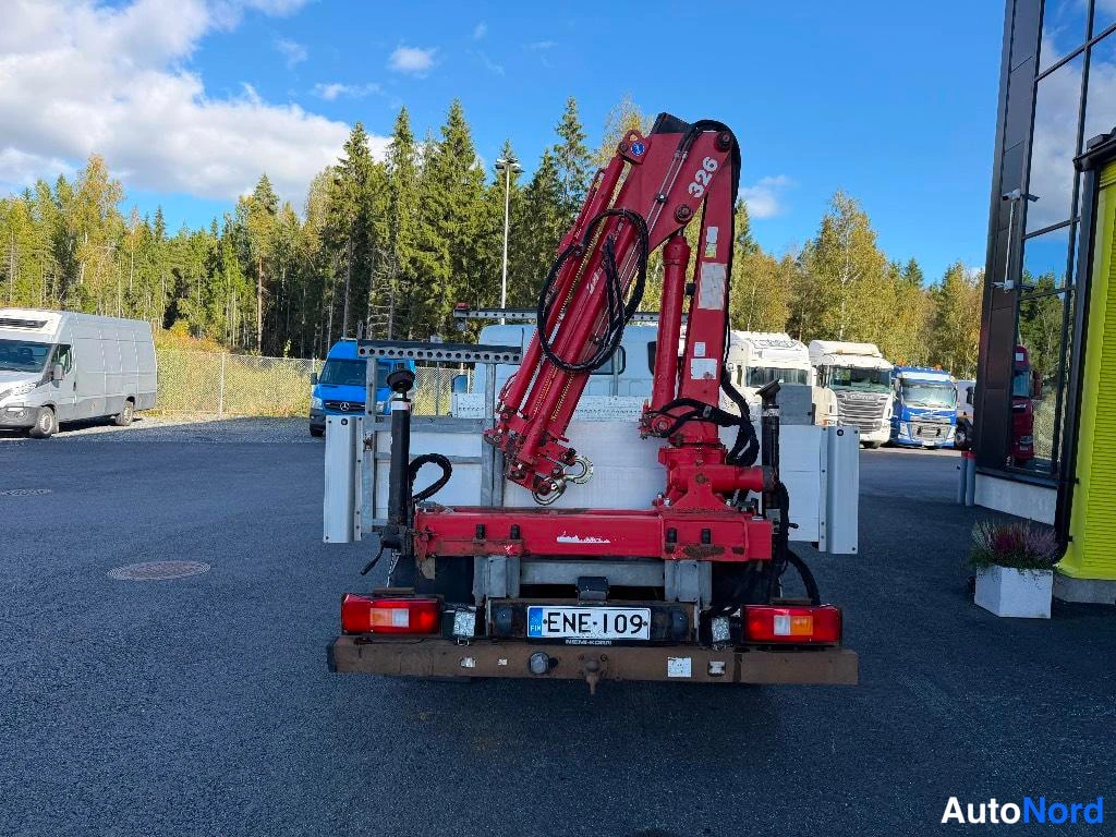 Takaa: Kuorma-auton takaosa suoraan takaa: punainen kuormausnosturi nostettuna, valkoinen lava ja rekisterikilpi.