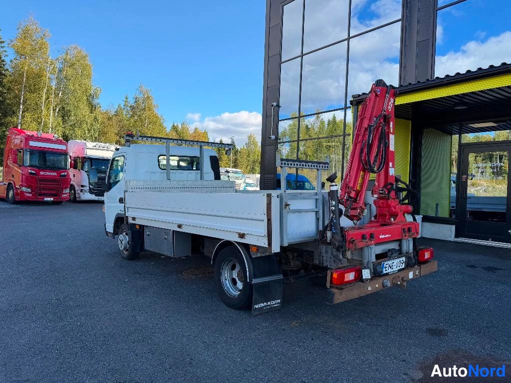 Takaviisto: Valkoisen Fuso-canter-lavan avolava takaa vasemmalta, punainen nosturi lavan perässä, rekisteri.