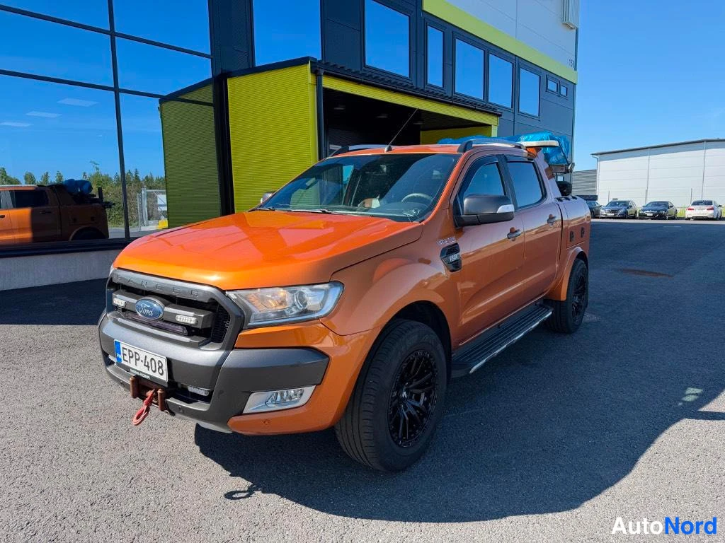 Etuviisto, nokka vasemmalle: Oranssi Ford Ranger -hina-auton etukulma vasemmalla, rekisteritunnus, sivupaneelit näkyvissä.