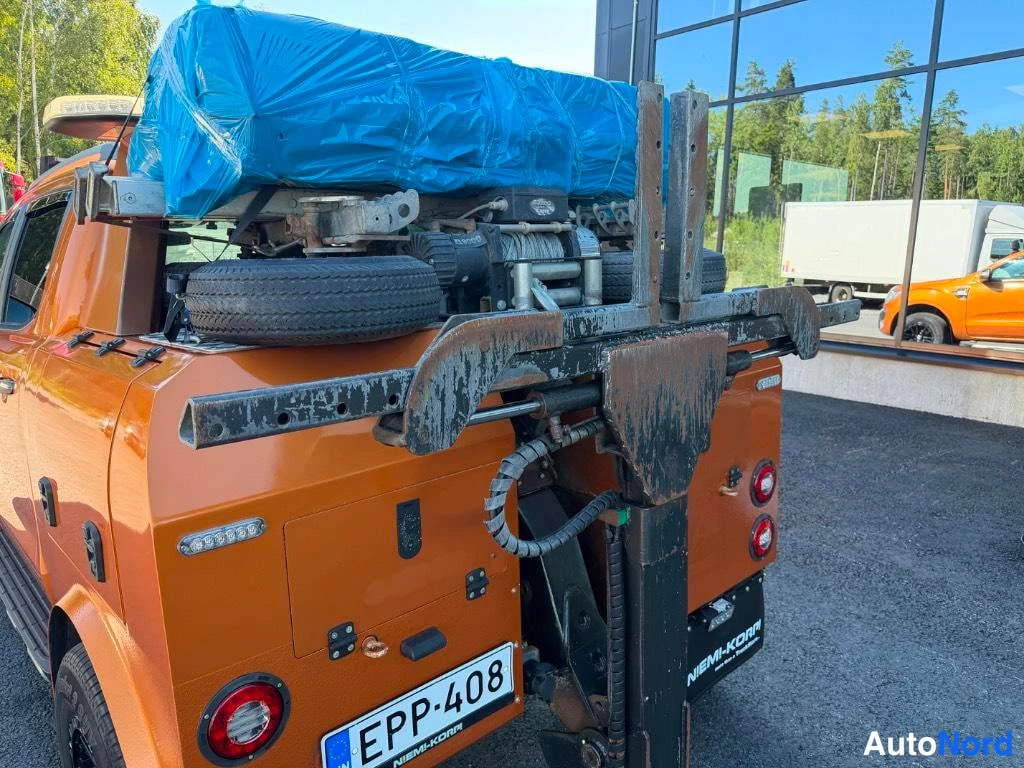 Takaviisto: Rear three-quarter view of the orange truck showing load, spare tire, and license plate.