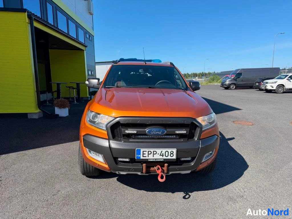 Edestä: Oranssin hina-auton etunäköyva; rekisterikilpi ja teksti NIEMI-KORPI etupuskurissa.