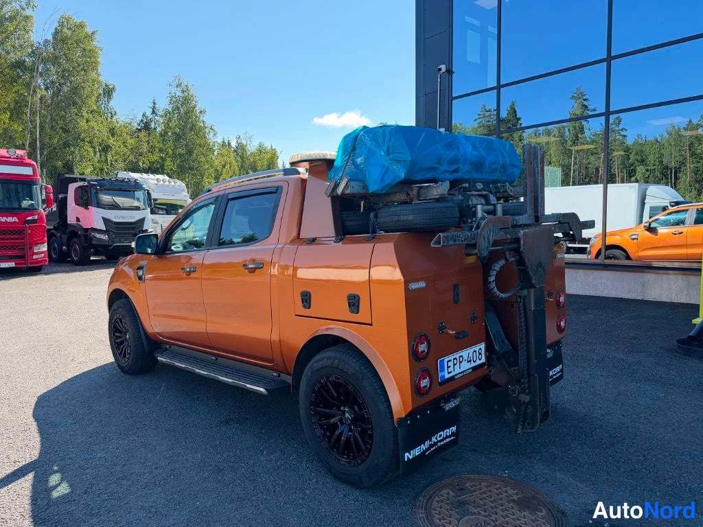 Takaviisto: Oranssi avolava-auto takaviistosta oikealta; lavalla sininen kuorma ja -kilpi.