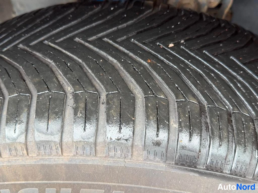Yksityiskohta: Lähikuva märästä auton renkaan kulutuspinnasta, vinoneliömäinen kuvio, kyljessä osittain näkyvä Goodyear-teksti.