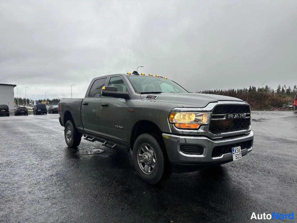 Etuviisto, nokka oikealle: RAM 2500 -nokka-auton etukulma, keula oikealla, harmaa kori ja avolava näkyvissä asfalttipihalla.