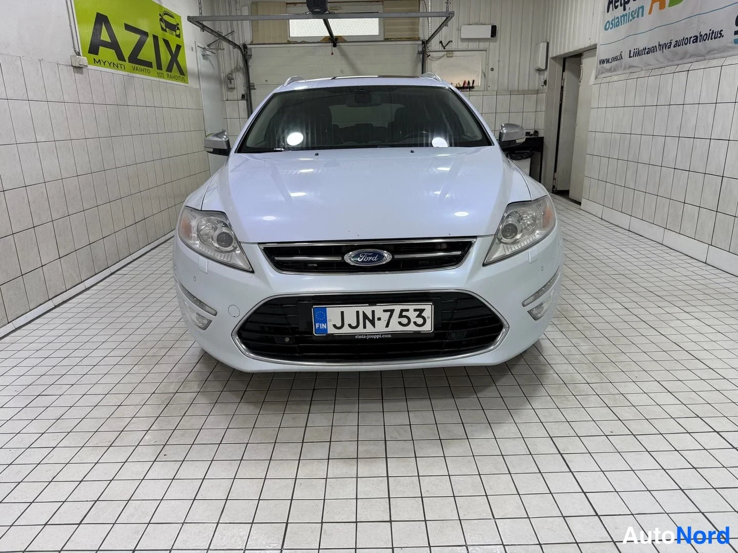 Edestä: Ford Mondeo Farmari suoraan edestä kuvattuna, valkoinen kori, rekisteritunnus.