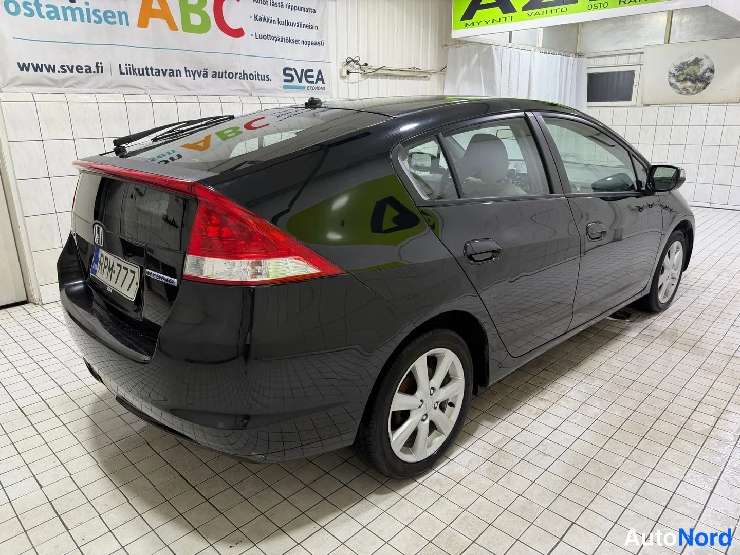 Takaviisto: Honda Insight -viistoperäisen takapää ja vasen sivu vaahteranruskea isolla takaluukulla, rekisterikilpi.