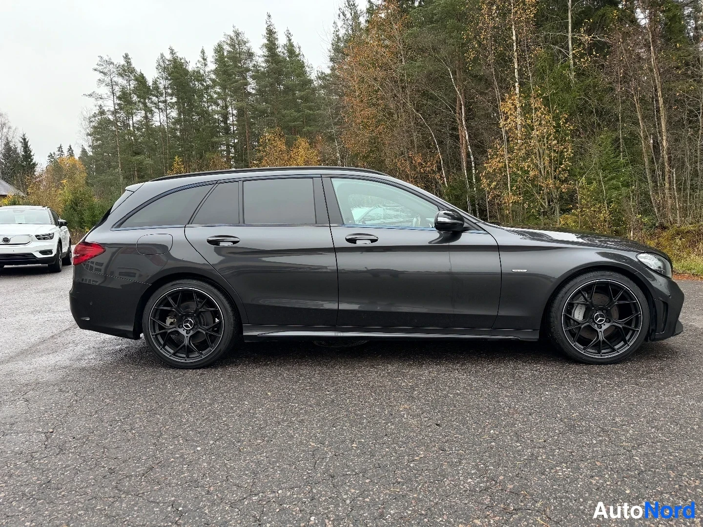 Sivulta: Tummanharmaa farmariauto sivulta vasemmalta, mustat vanteet ja tummat ikkunat näkyvissä.