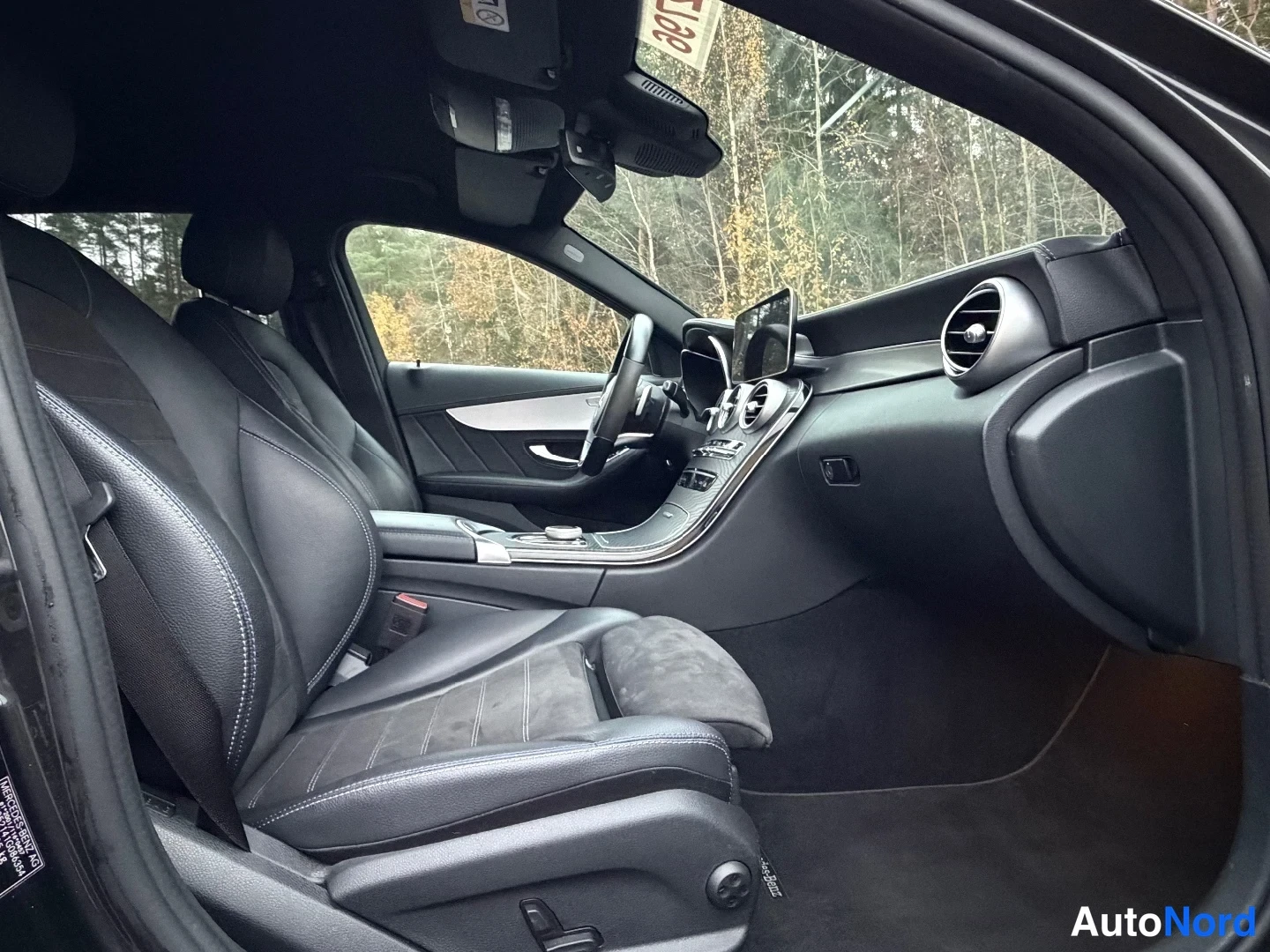 Muu: Mercedes-Benzin etuistuin ja kojelauta ovasta katsottuna: tummat istuimet, infotainment-näytön teline ja pyöränkulmajarrutus