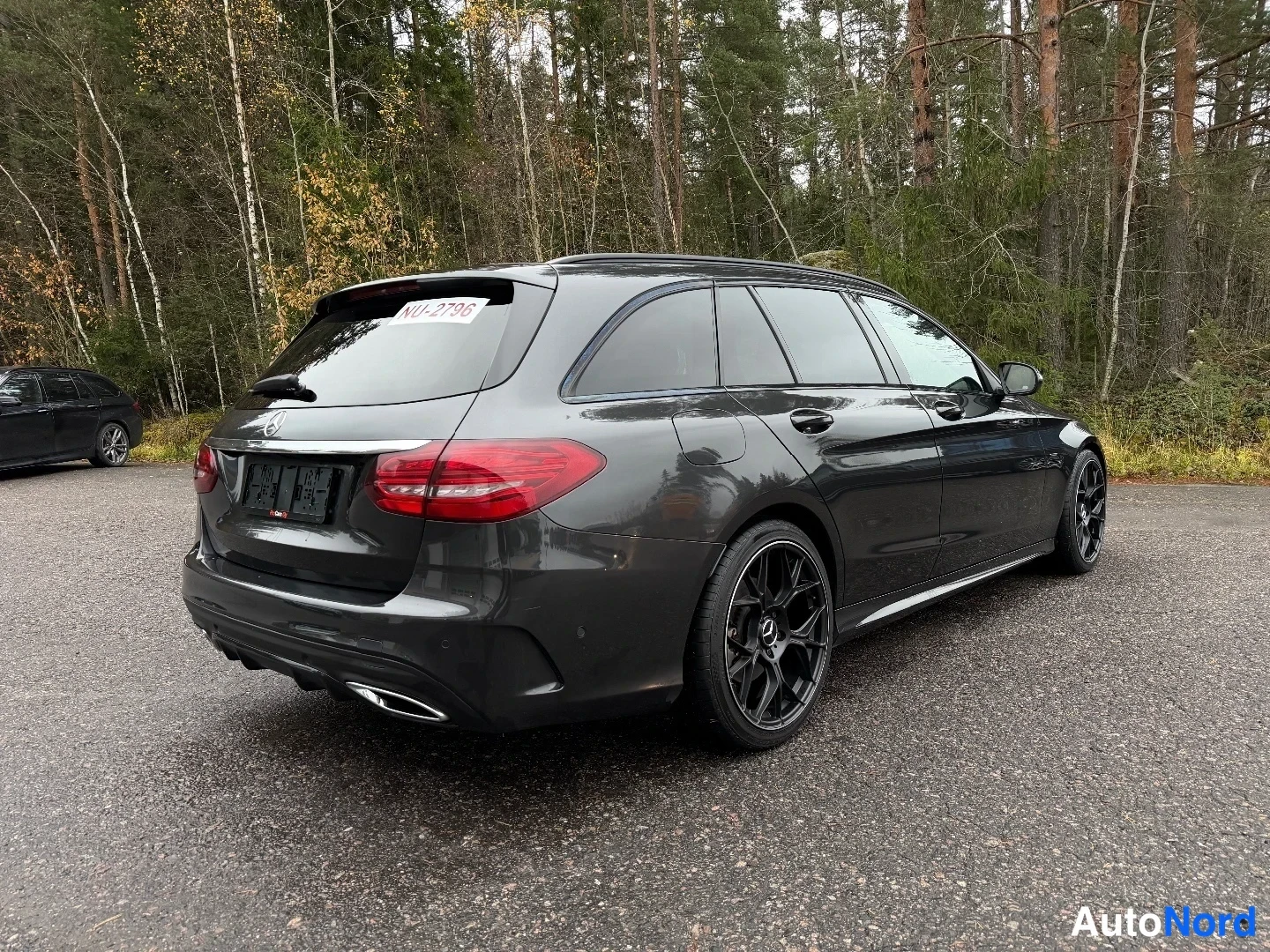 Takaviisto: Mercedes-Benz C-sarjan farmariauto takaa viistosti kuvattuna, tummanharmaa kori, mustat kevytmetallivanteet, rekisterikilpi peitetty.