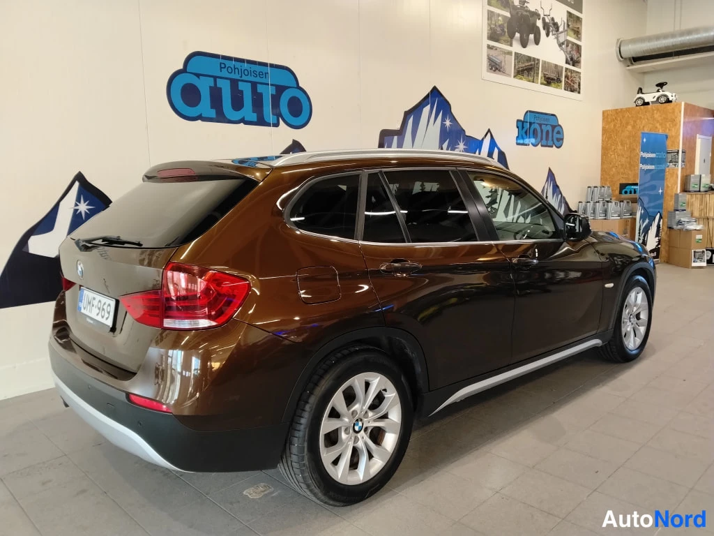 Takaviisto: BMW X1 -kombi takaa kulmasta kuvattuna; ruskea kori, rekisterikilpi, katuki sperit ja alumiinivanteet.