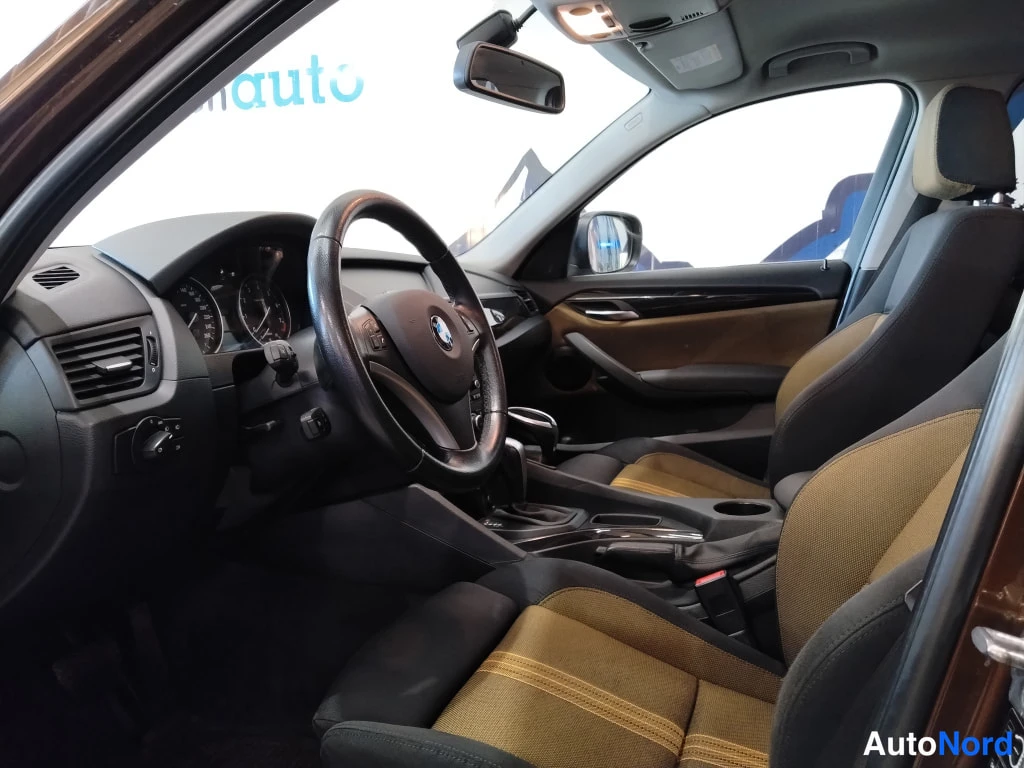 Muu: Auton etupenkki ja ohjaamo: BMW-ohjauspyörä, mittaristo ja ruskeakuvioiset kankaanistuimet.