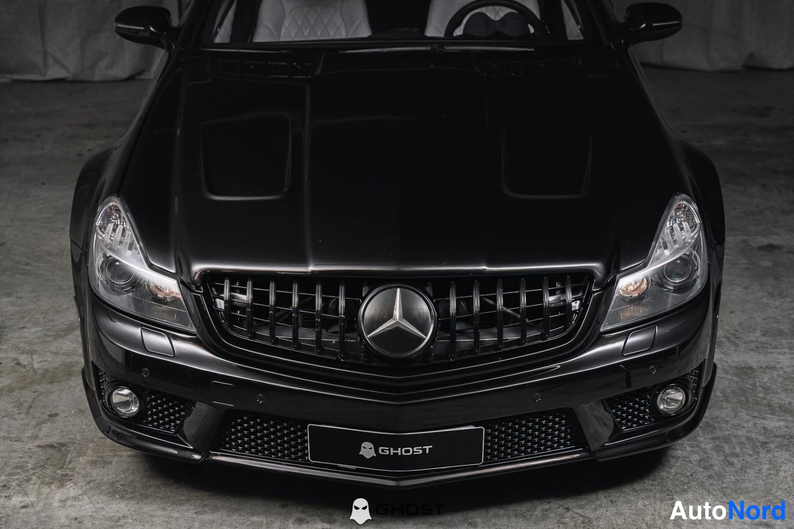 Edestä: Lähikuva mustan Mercedes-Benzin etuosasta ylhäältä: kylkilattia ja perävaunu valmiina tunnistettavaksi, valoireset selvästi näkyvillä.