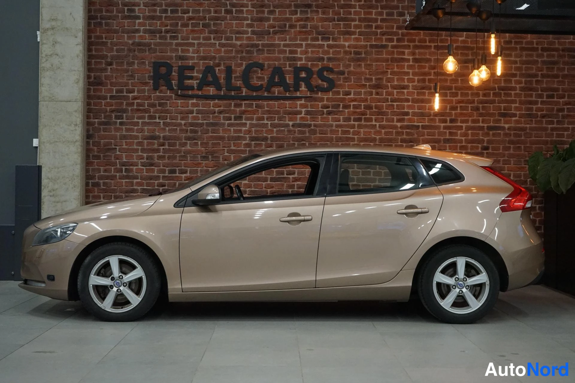 Sivulta: Volvo V40 sivulta kuvattuna, keula vasemmalla, vaalean beige koriväri ja hopeiset kevytmetallivanteet.