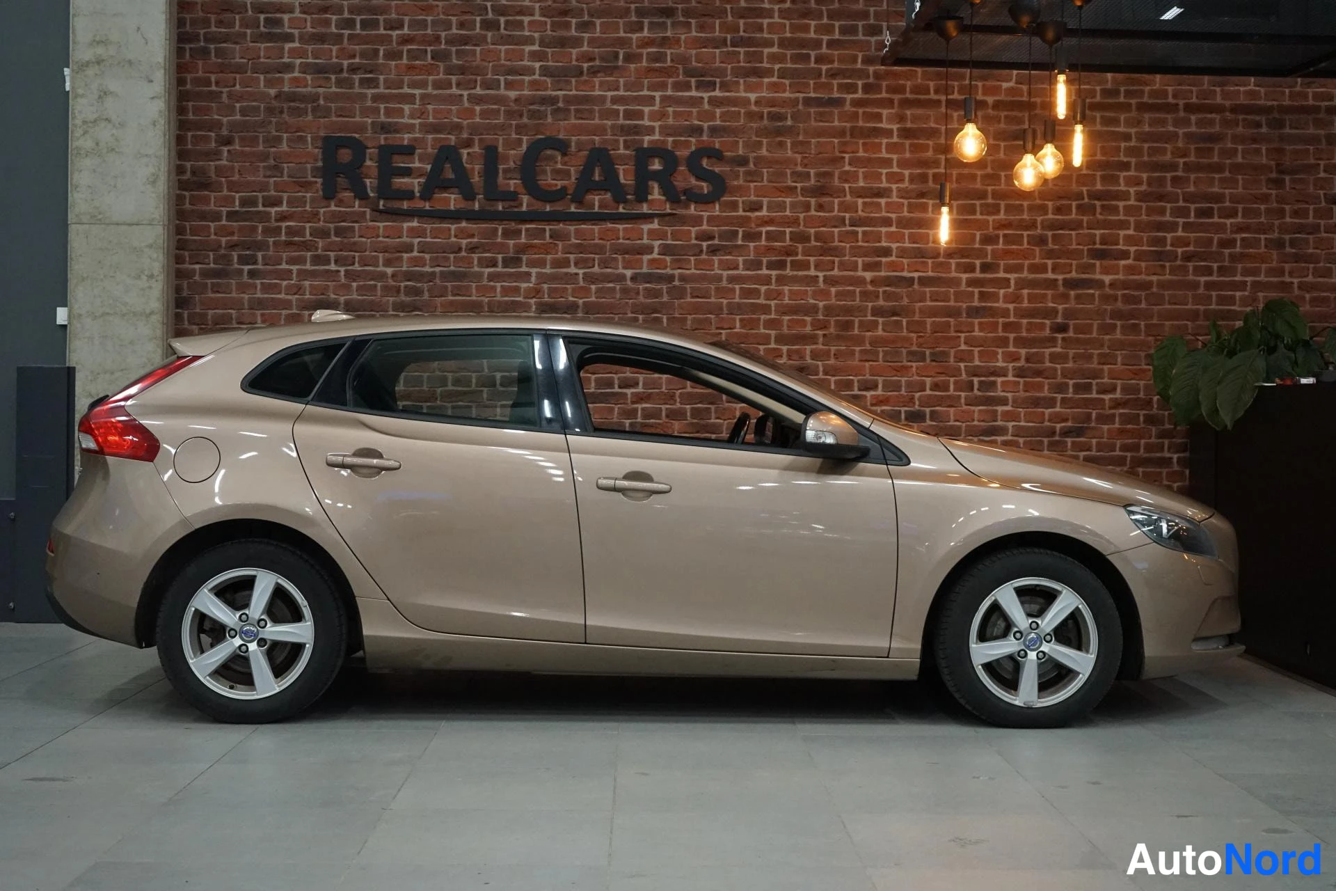 Sivulta: Volvo V40 sivulta kuvattuna, perä vasemmalla, vaalean beige koriväri ja hopeiset kevytmetallivanteet.