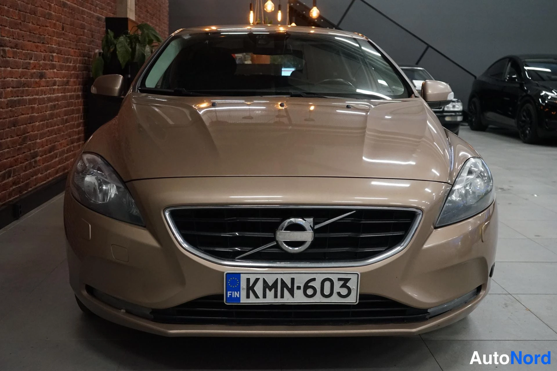 Edestä: Beige Volvo V40 edestä päin, rekisterikilpi.