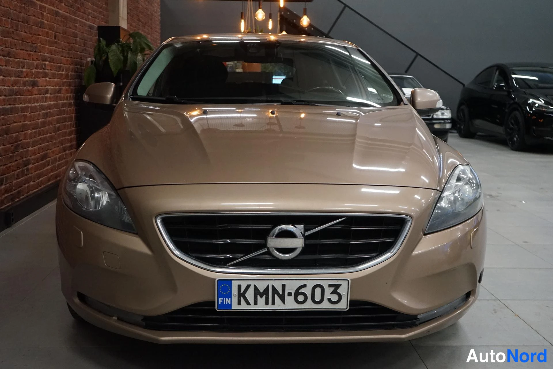 Edestä: Beige Volvo V40 suoraan edestä kuvattuna, rekisterikilpi.