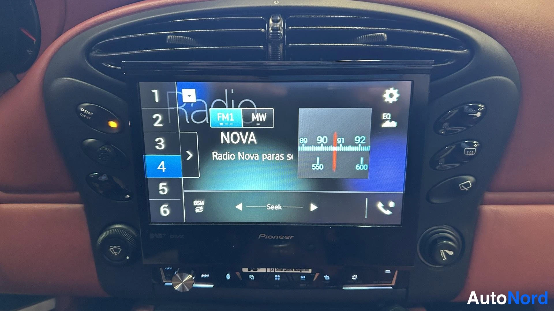 Yksityiskohta: Kojelaudan keskikonsolin lähikuva: Pioneer-radiolaite, näytöllä radio FM1, kanava 4, teksti 'NOVA' ja taajuusasteikko 89–92.