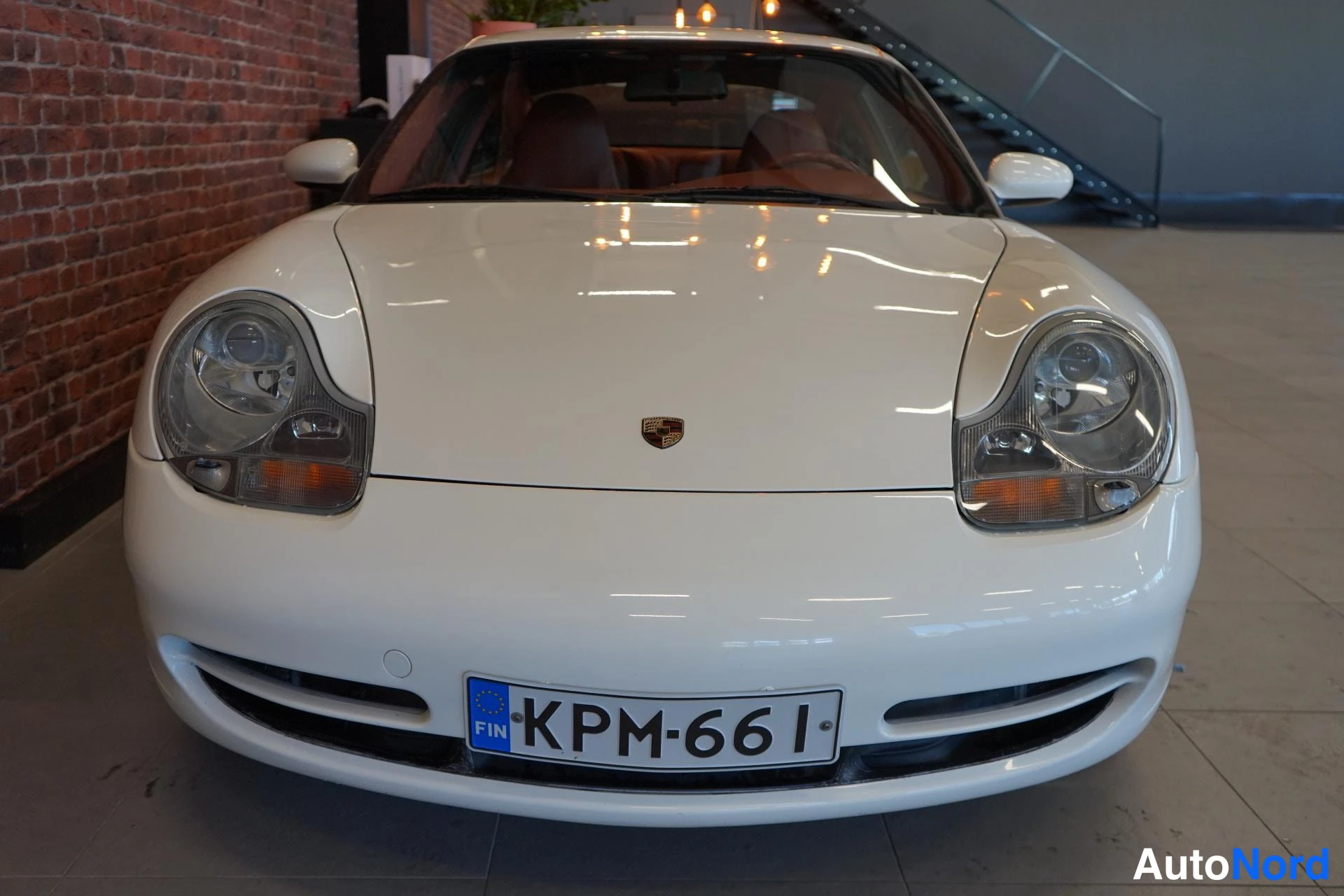 Edestä: Valkoisen Porsche 911:n etunäkymä; konepellissä Porsche-tunnus ja rekisterikilpi.