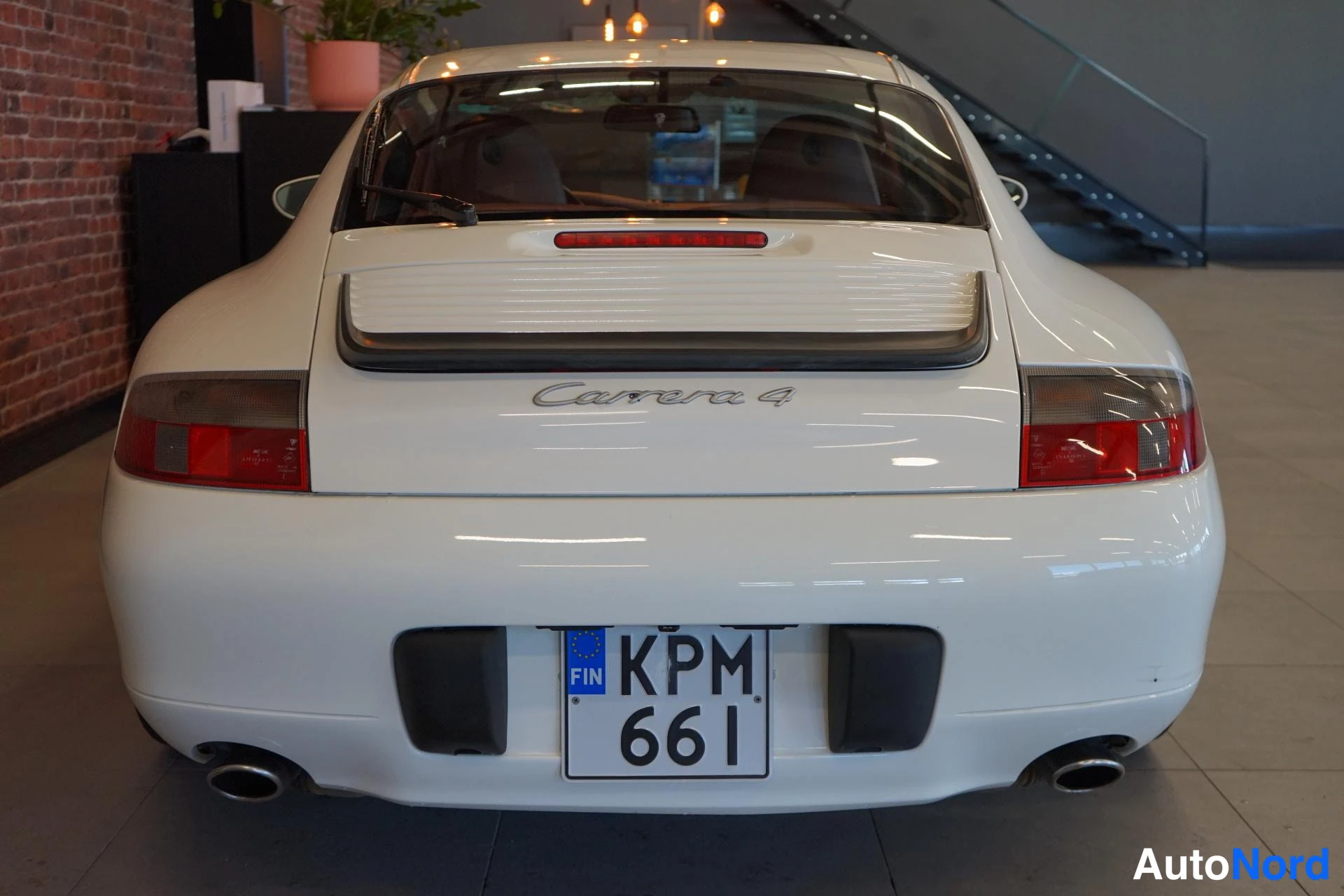 Takaa: Valkoisen Porsche 911 Carrera 4:n takanäkymä suoraan takaa; kannessa voi näkyä teksti Carrera 4, rekisterikilpi KPM 661.