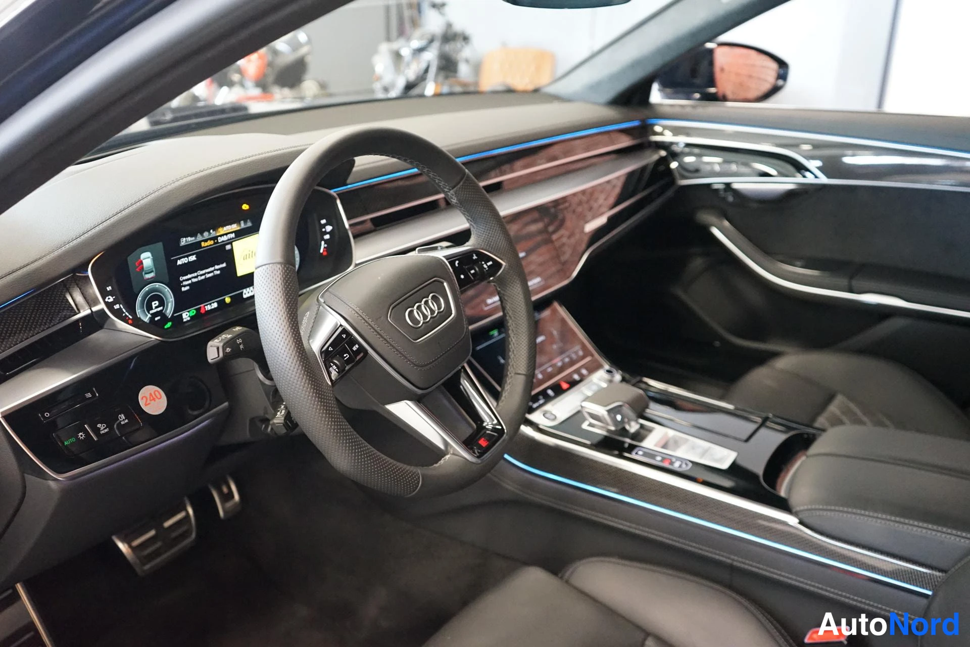 Sivulta: Audi A8in ohjaamo kuljettajan puolelta: Audi-multifunktiohirri, digitaalinen mittaristo ja keskitunnelin kosketusnäytöt.
