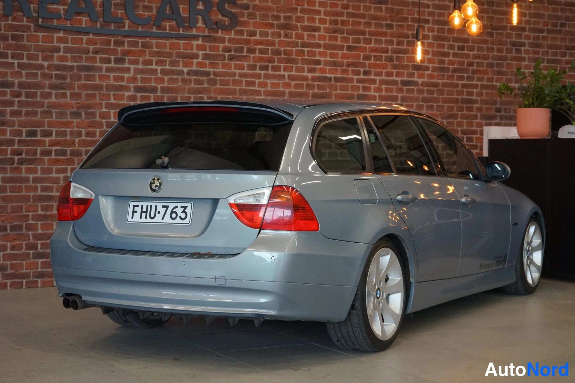 Takaviisto: BMW 325 -farmari takaviistolta vasemmalta, hopeanharmaa, rekisteritunnus.