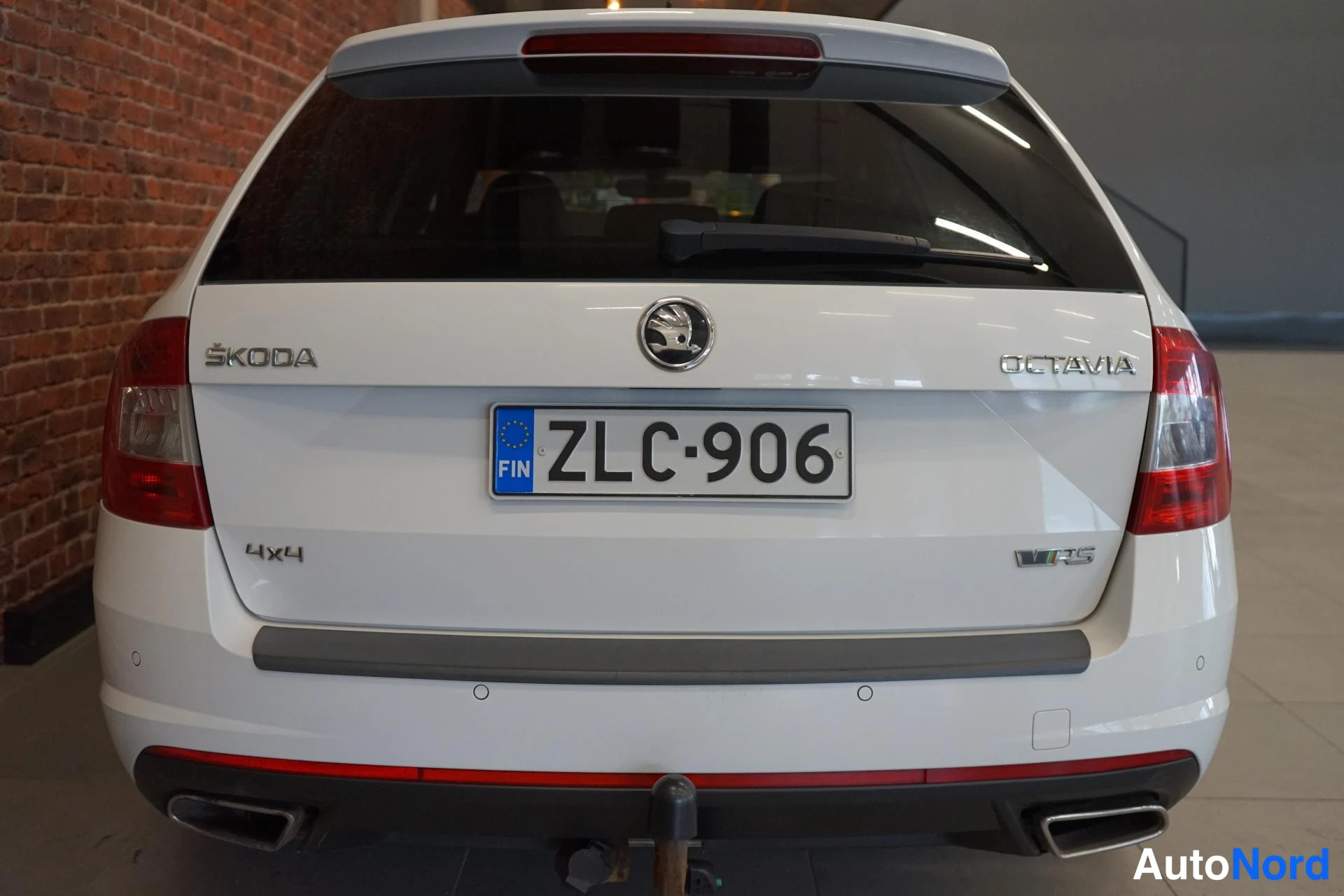 Takaa: Valkoisen farmariauton perä, Škoda Octavia -merkinnät, 4x4-tunnus ja kaksiosaiset pakoputkien suuttimet, rekisterikilpi.