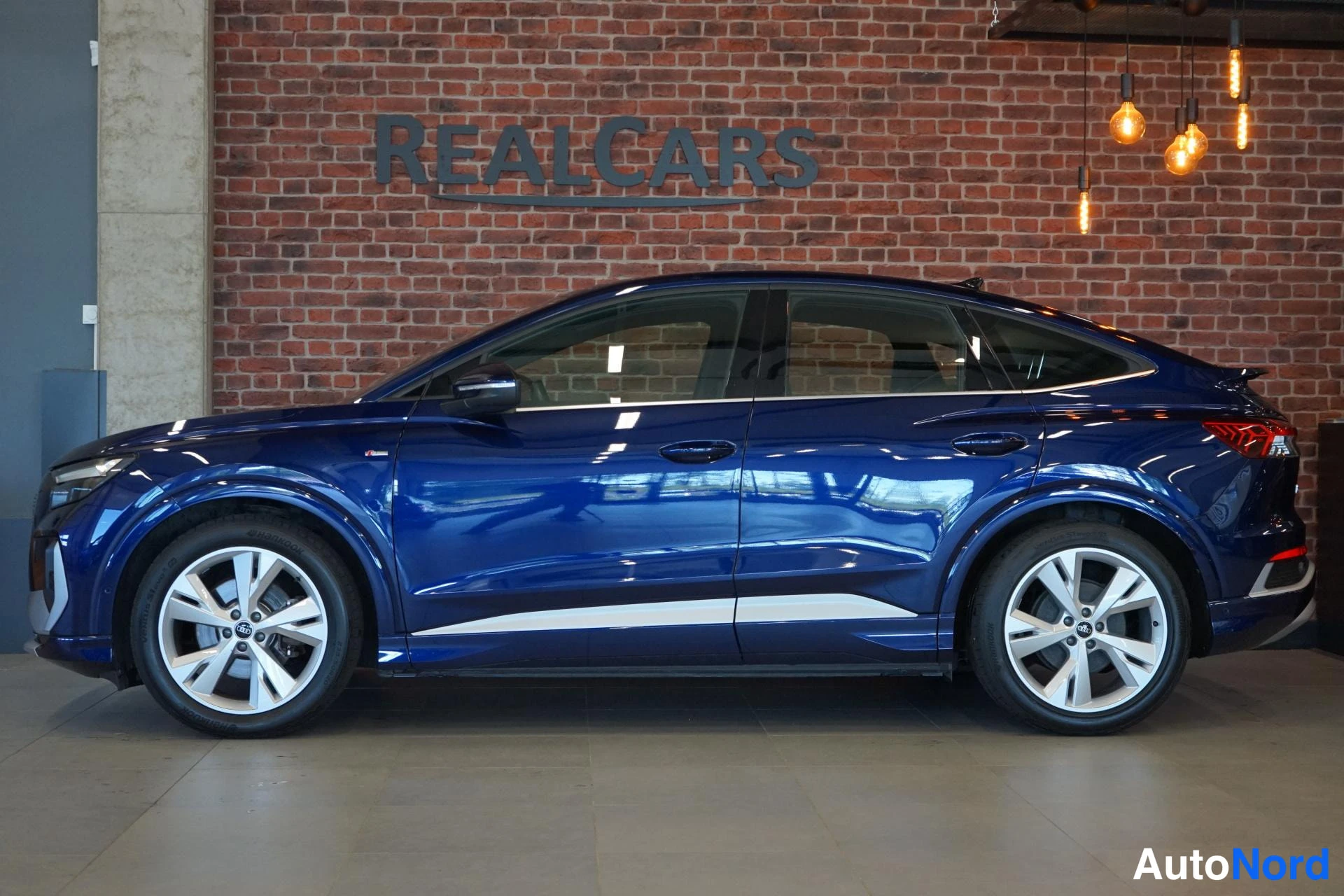 Takaviisto: Sininen Audi Sportback -maasturin sivuprofiili, neljä hopeata vanetta ja korin alareunassa kromilista.