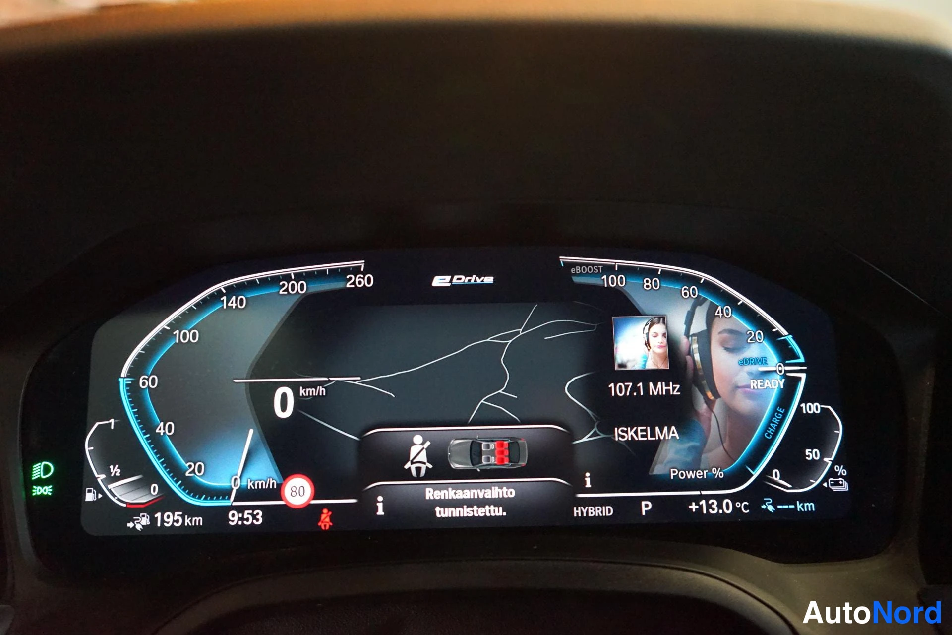 Edestä: Digitaalinen mittaristo: nopeus 0 km/h, matka 195 km, HYBRID ja P-merkintä, lämpötila +13,0 °C ja teksti Renkaanvaihto tunnistettu.