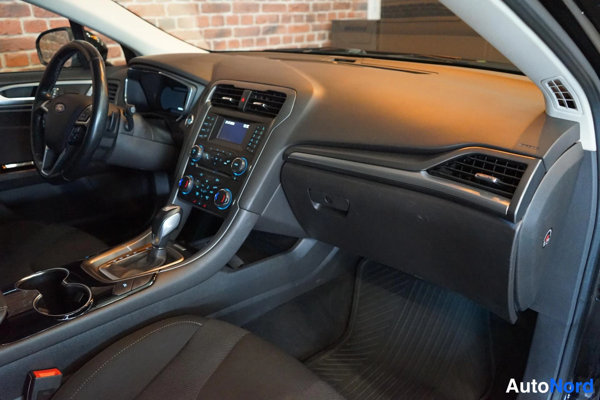 Etuviisto: Ford Mondeo - kojelauta ja keskikonsoli, automaattivaihteiston valitsin, kosketusnäyttö ja kahden kupin pitimet.