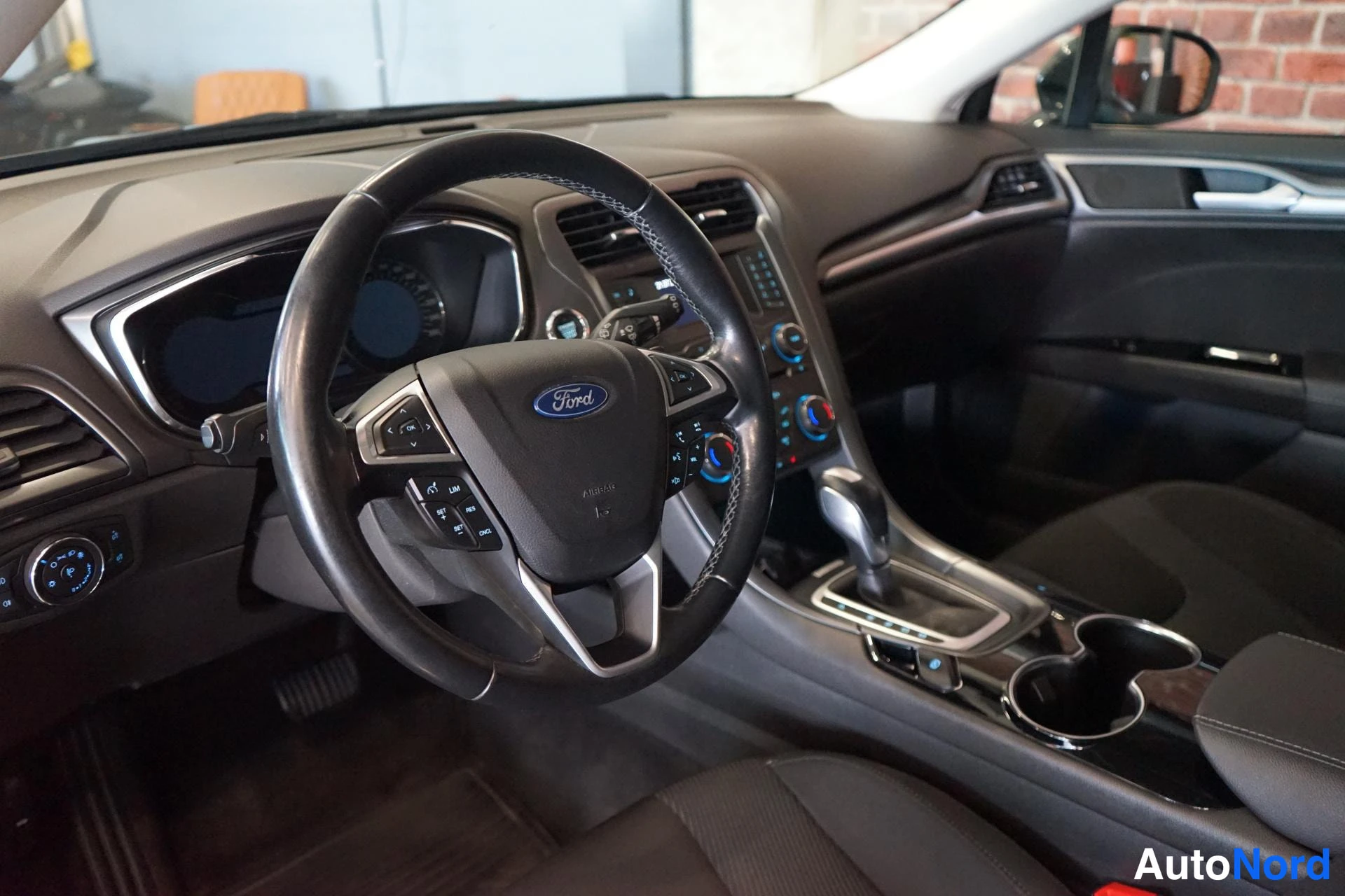 Muu: ratin Ford-logo, automaattivaihteen valitsin ja infotainment-paneeli näkyvät.