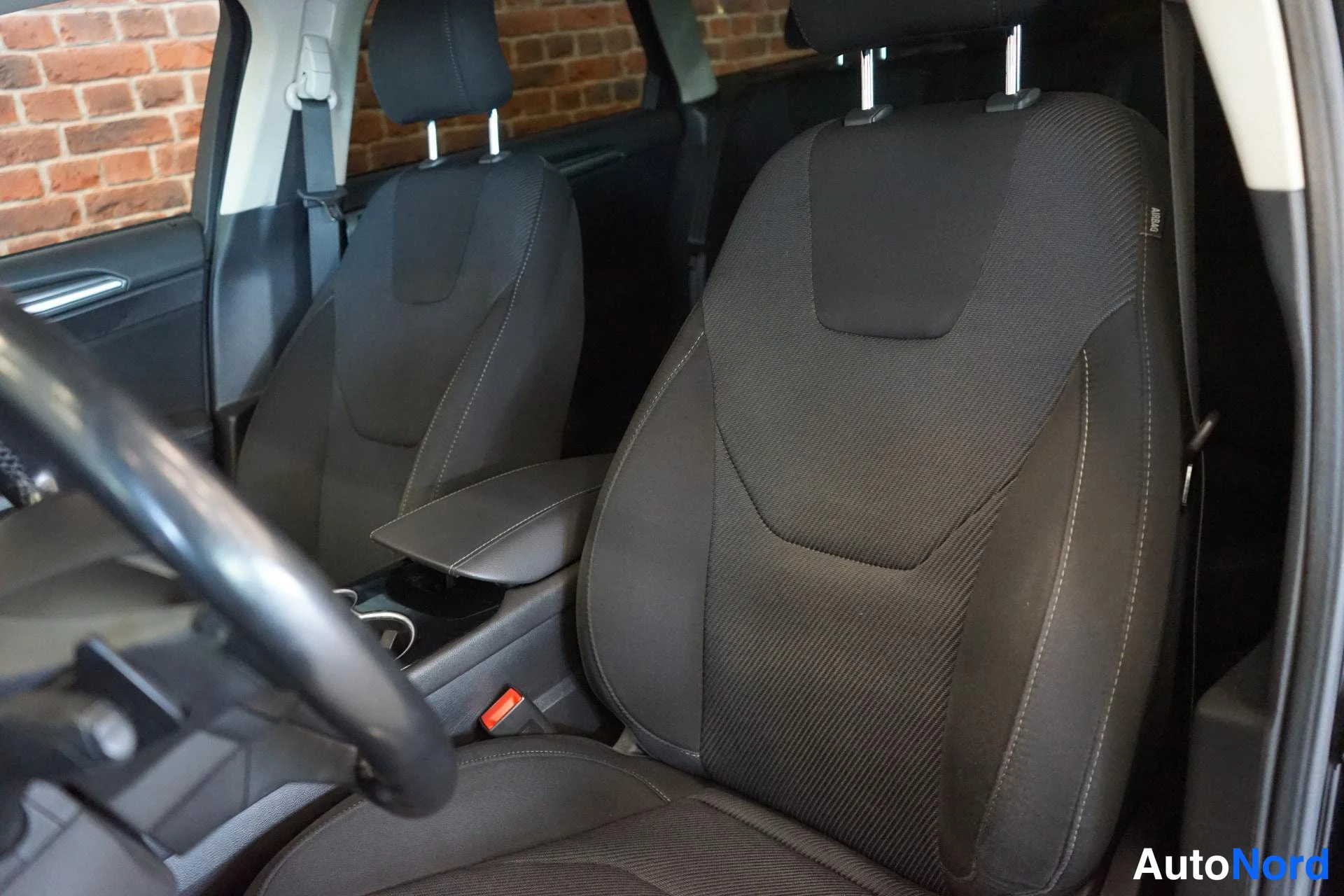 Etuviisto: Ford Mondeo - tumma kankaupäällysteinen etuistuin ja kuljettajan istuin sisätiloissa, kuljettajan ovi auki.