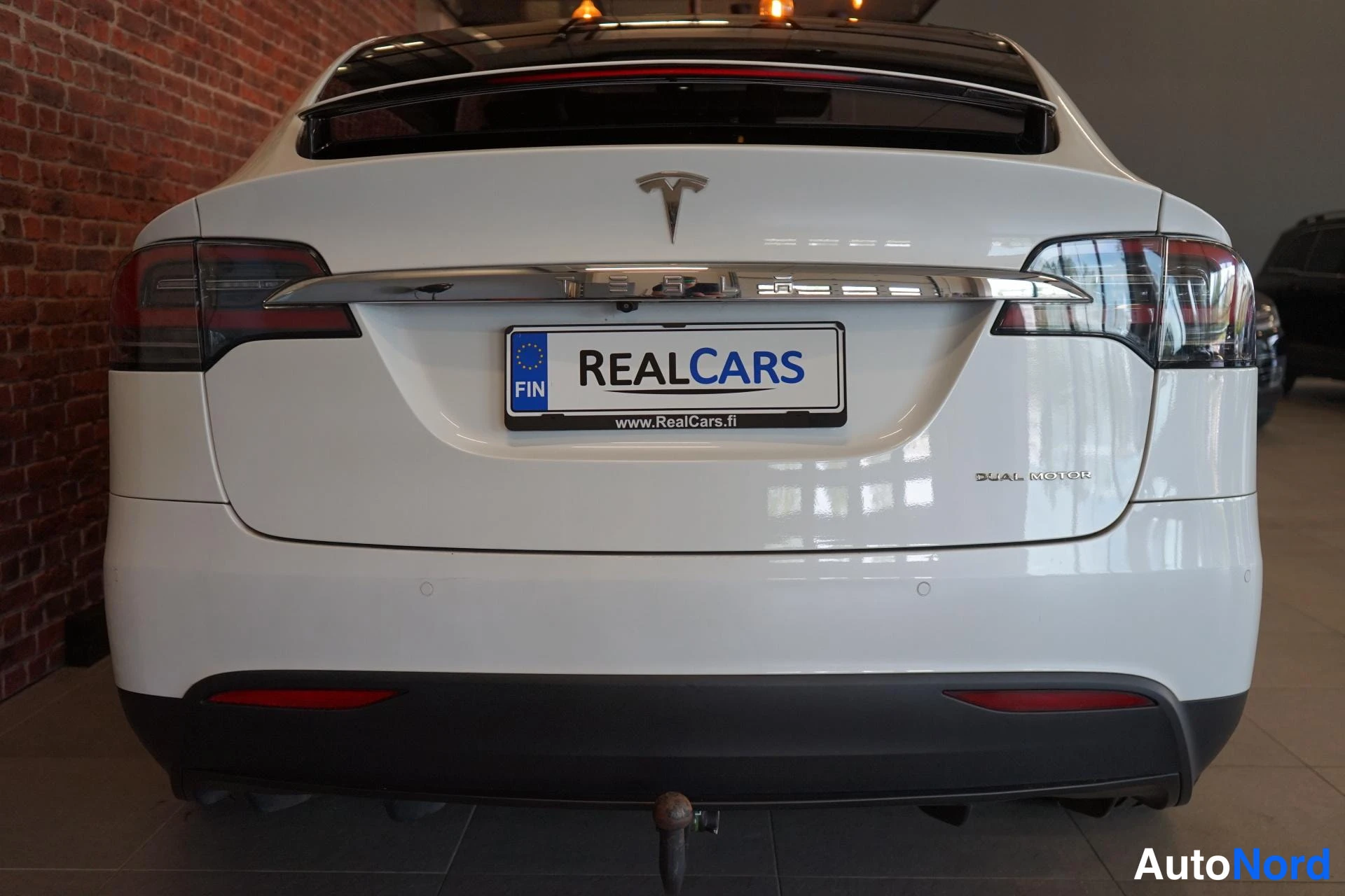 Takaa: Valkoisen Tesla Model X:n takanäkyvissä: TUNTEMATTOMAN mallin takavalot ja takapuskki ovat näkyvissä; auto on valkoinen.