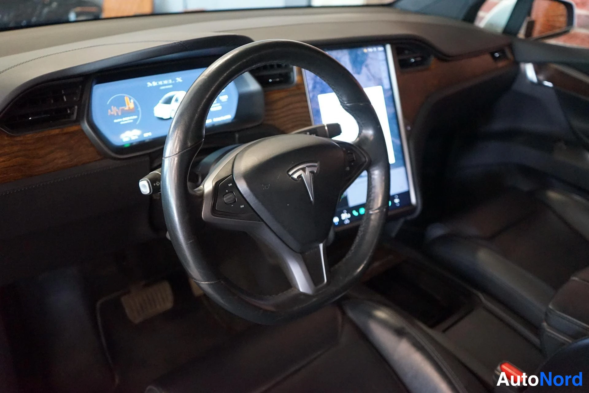 Muu: Tesla Model X:n ohjaamo: puukuviollinen kojelauta, ohjauspyörä ja keskellä suuri kosketusnäyttö. Kyseessä on tuntematon malli.